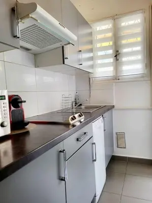 a kitchen with white cabinets and a black counter top at Cosy Studio à Cannes 8 min de la Croisette in Cannes