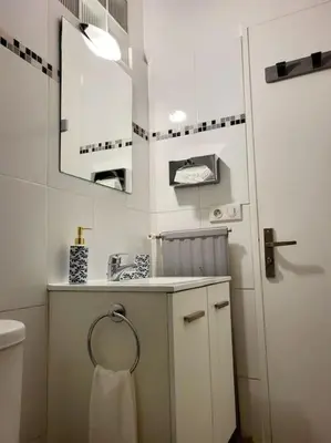 a white bathroom with a sink and a mirror at Cosy Studio à Cannes 8 min de la Croisette in Cannes