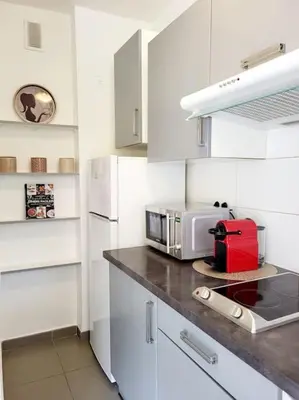 a white kitchen with a counter top with a microwave at Cosy Studio à Cannes 8 min de la Croisette in Cannes