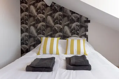 a white bed with yellow and white pillows on it at Duplex Pradignac by Halldis in Cannes