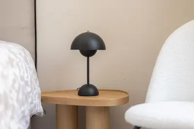 a black lamp on a wooden table next to two chairs at Splendide et idéalement situé proche du palais. in Cannes