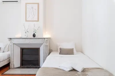 two beds in a white room with a fireplace at BARBARA by Terry's Homes in Cannes
