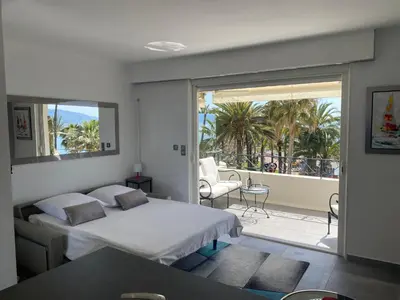a bedroom with a bed and a balcony with palm trees at Studio mer Croisette in Cannes