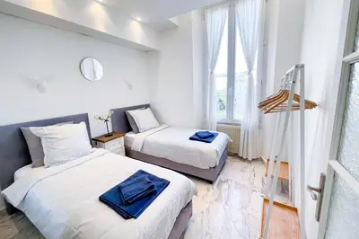 two beds in a room with white walls and windows at Le Borniol, splendid 3 bedrooms Appt, Cannes Center in Cannes