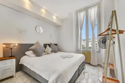 a white bedroom with a large bed and a window at Le Borniol, splendid 3 bedrooms Appt, Cannes Center in Cannes