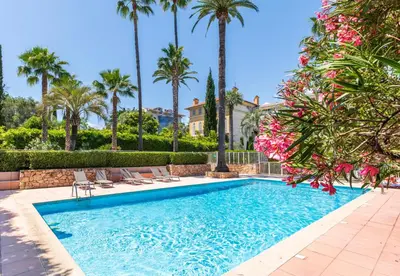 a swimming pool with chairs and palm trees at La Palmeraie - Piscine et Toit Terrasse in Cannes
