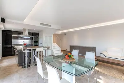 a dining room and kitchen with a glass table and chairs at La Palmeraie - Piscine et Toit Terrasse in Cannes
