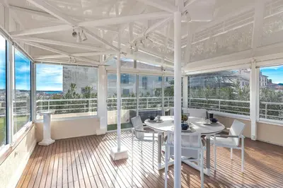 a white room with a table and chairs and windows at La Palmeraie - Piscine et Toit Terrasse in Cannes