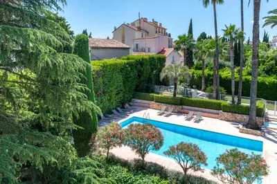 a swimming pool in a yard with trees and a building at La Palmeraie - Piscine et Toit Terrasse in Cannes