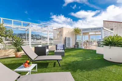 a patio with a lawn with chairs and plants at La Palmeraie - Piscine et Toit Terrasse in Cannes