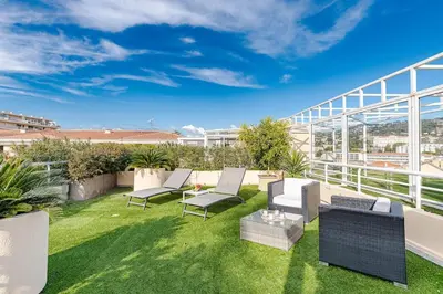 a patio with chairs and tables on a balcony at La Palmeraie - Piscine et Toit Terrasse in Cannes