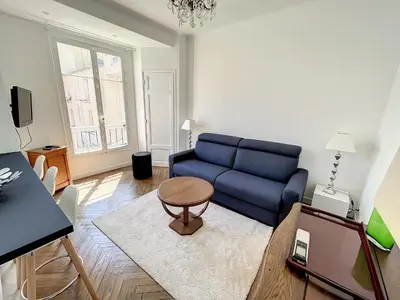 a living room with a blue couch and a table at 1 bedroom Palais Hoche Cannes 5 mins from the Croisette Cannes Riviera 226 in Cannes