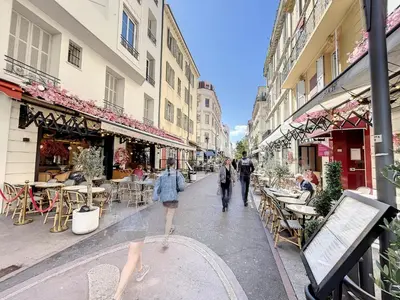 two people walking down a street with tables and chairs at 1 bedroom Palais Hoche Cannes 5 mins from the Croisette Cannes Riviera 226 in Cannes