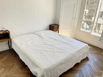 a white bed in a room with a window at 1 bedroom Palais Hoche Cannes 5 mins from the Croisette Cannes Riviera 226 in Cannes