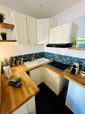a kitchen with white cabinets and a wooden counter top at Agréable T2 rénové, Cannes centre, Suquet, plages in Cannes