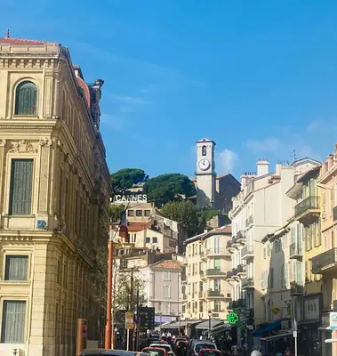 a busy city street with buildings and a clock tower at Agréable T2 rénové, Cannes centre, Suquet, plages in Cannes