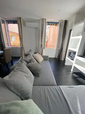 a large bed sitting in a room with windows at Agréable T2 rénové, Cannes centre, Suquet, plages in Cannes