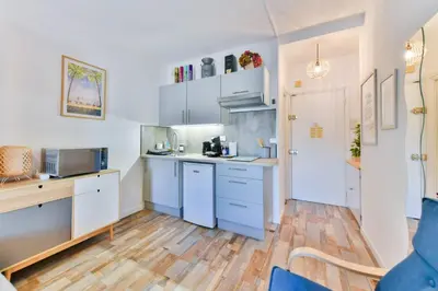 a kitchen with white cabinets and a wooden floor at LE FESTIF splendide studio avec loggia au Carré d'Or in Cannes