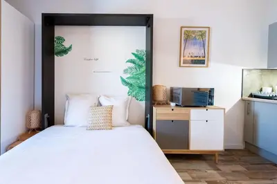a bedroom with a bed and a desk with a television at LE FESTIF splendide studio avec loggia au Carré d'Or in Cannes