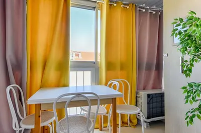 a table and chairs in a room with curtains at LE FESTIF splendide studio avec loggia au Carré d'Or in Cannes