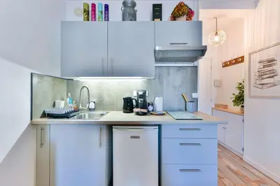 a kitchen with white cabinets and a sink at LE FESTIF splendide studio avec loggia au Carré d'Or in Cannes