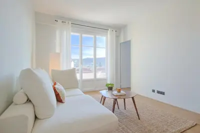 a white living room with a white couch and a table at L'impérator by Winsome Destination in Cannes