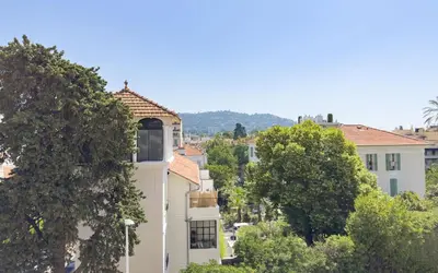 a tall white building with trees in the foreground at L'impérator by Winsome Destination in Cannes