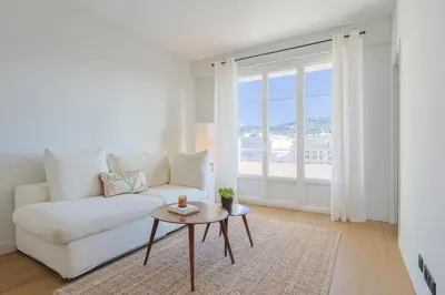 a living room with a white couch and a table at L'impérator by Winsome Destination in Cannes