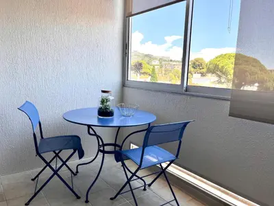 a blue table and chairs in a room with a window at La douceur de vivre à Cannes in Cannes