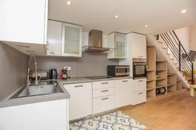 a kitchen with white cabinets and a sink and a staircase at IMMOGROOM - Beautiful Duplex - 5 min from the beach - AC - SUQUET in Cannes