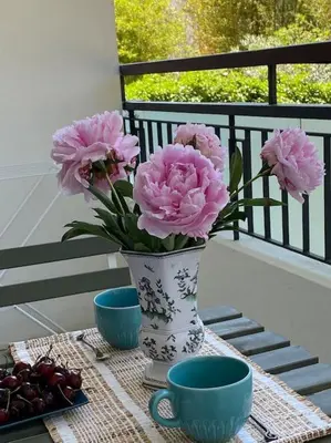 a vase with pink flowers on a table with two cups at Joli studio calme et central in Cannes