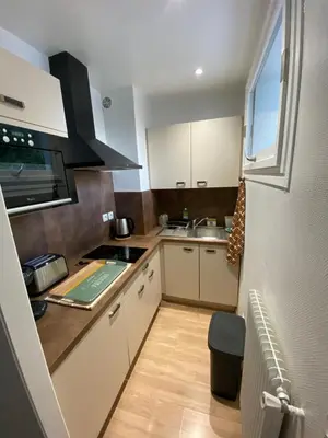 a kitchen with white cabinets and a sink and a window at Joli studio calme et central in Cannes