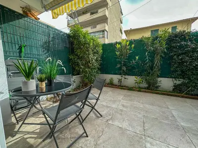 a patio with a table and chairs and a fence at COSY MADRID, appartement proche de la mer in Cannes