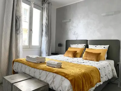 a bedroom with a large bed with yellow and white sheets at Elegant studio proche Palais des Festivals in Cannes