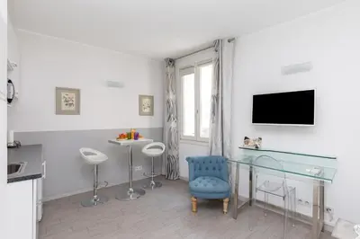 a living room with a glass table and a blue chair at Elegant studio proche Palais des Festivals in Cannes