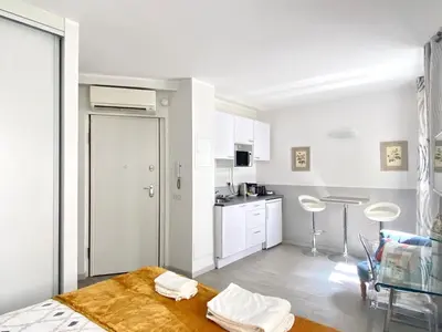 a living room with a table and a kitchen at Elegant studio proche Palais des Festivals in Cannes