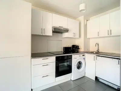 a kitchen with white cabinets and a washing machine at 2p Cannes centre-ville Terrasse in Cannes