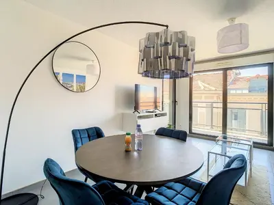 a dining room with a table and chairs and a mirror at 2p Cannes centre-ville Terrasse in Cannes