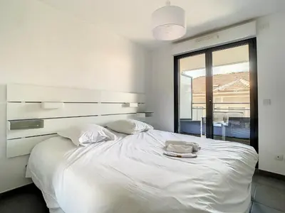 a white bedroom with a large white bed with two pillows at 2p Cannes centre-ville Terrasse in Cannes