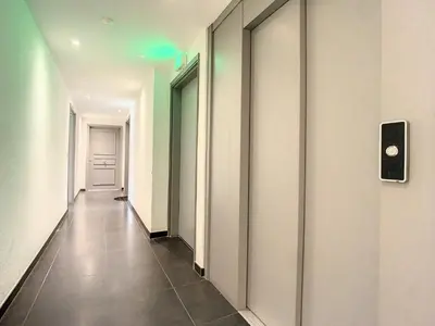 a hallway with white walls and tile floors and a green light at 2p Cannes centre-ville Terrasse in Cannes
