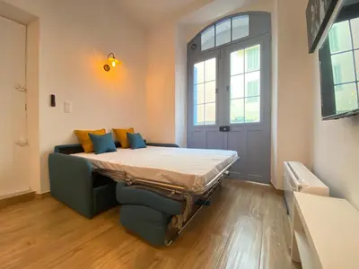 a bed in a room with a couch and a window at Le Perrissol By SCLS Locations in Cannes