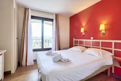 a bedroom with a white bed with a red wall at Résidence Cannes Villa Francia - maeva Home - Appartement vue mer 3 pièces 6 personnes - Prestige MAE-9674 in Cannes