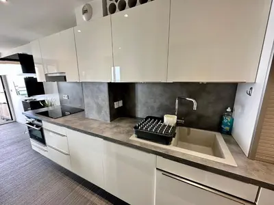 a kitchen with white cabinets and a sink at Beau T2 avec terrasse vue mer in Cannes