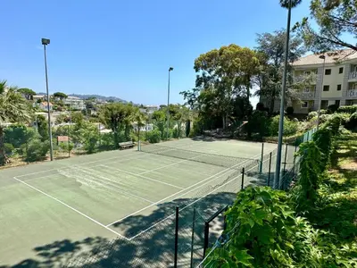 a tennis court with a net and a tennis ball at Beau T2 avec terrasse vue mer in Cannes