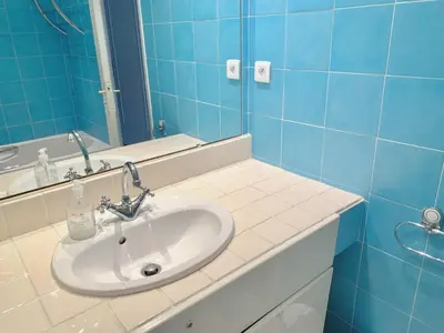 a bathroom with a sink and a mirror and blue tiles at Appartement front de mer, 80M2 (3P), Piscine & Mer in Cannes