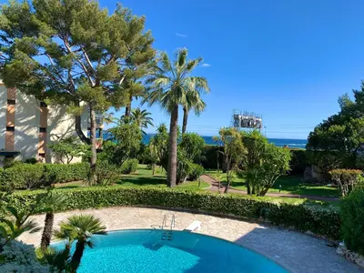 a resort with a swimming pool and palm trees at Appartement front de mer, 80M2 (3P), Piscine & Mer in Cannes