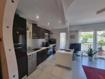 a kitchen with black and white appliances and a table at Appartement Beauvallon in Cannes