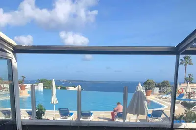 a man sitting on a patio next to a swimming pool at Quiet sea view with pool in Cannes