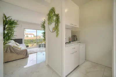 a kitchen with white cabinets and a living room at Lumineux Studio TERRASSE, Clémenceau-CANNES CENTRE A0B192 in Cannes