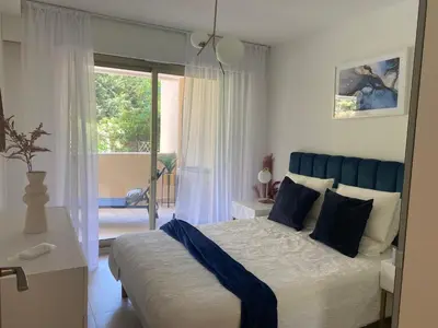 a bedroom with a bed with a blue headboard and a window at Elegant apartment close to Croisette and Palais de Festival with garage in Cannes